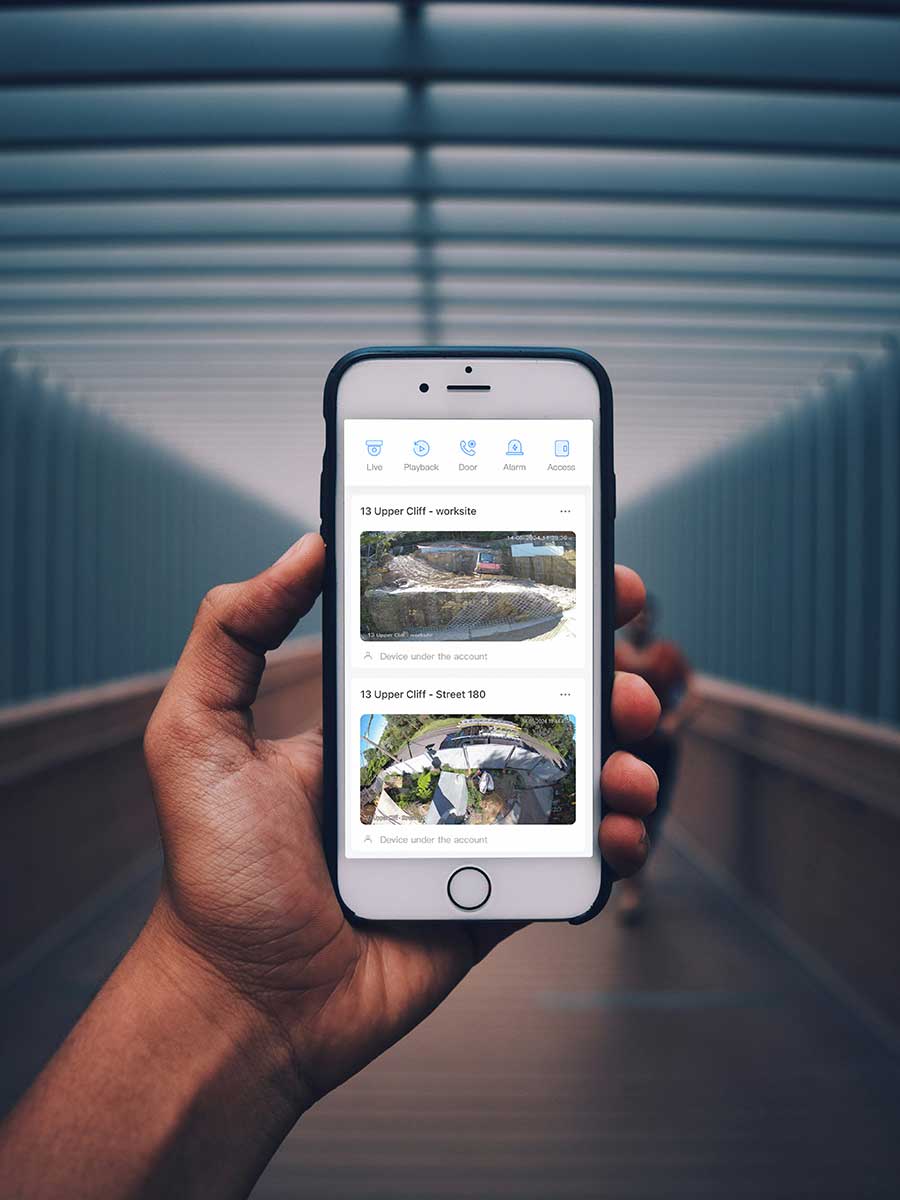 Hand holding Smartphone showing DarkGuard Security Mobile App with real-time LIVE view of a construction site.